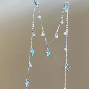 Detailed view of silver box chain necklace with blue starfish shells and pearls
