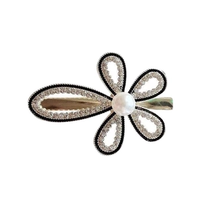 Gold metal hair clip with crystal-encrusted flower shape and a white center pearl