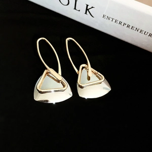 Macro shot of geometric gold hollow triangle earrings with white fan-shaped pendants
