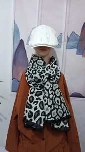 Close-up of black and white leopard print scarf with fringe and white beret on a mannequin