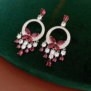 Macro shot of silver earrings with red marquise and white teardrop crystals on velvet