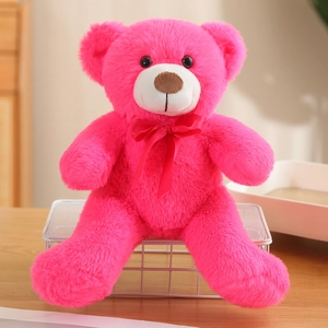 Detail of soft rose pink teddy bear plush with a red silk ribbon bow on a shelf