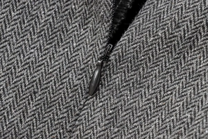 Macro detail of high-quality grey herringbone wool fabric and hidden black metal zipper