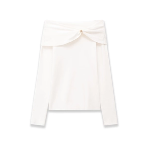 Detail of white off-the-shoulder knit top featuring a knot twist and gold ornament