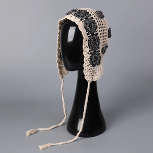 Detailed view of handmade crochet floral hat with beige base and black knitted flowers