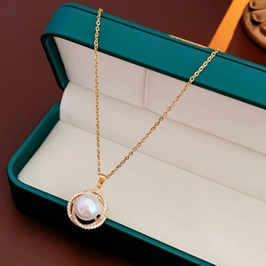 Detail einer Goldkette mit weißer Perle und Kristallen in einer grünen Schmuckschatulle