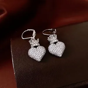 Boucles d'oreilles cœur couronne en argent avec zircons sur fond de soie rouge élégant