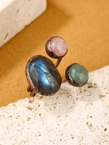 Macro detail of vintage copper ring with labradorite and rose quartz on stone