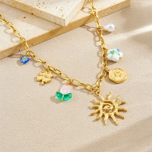 Gold stainless steel sun necklace with clover tulip and pearl charms on stone background