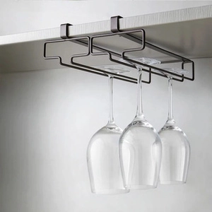 Detail of dark brown metal wine glass rack holding three glasses under white shelf