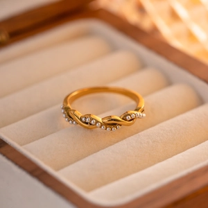 Macro view of gold twisted metal ring band set with elegant white pearls on velvet