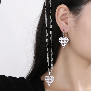 Model wearing silver hollow heart pendant paperclip chain necklace and matching earrings set