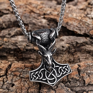 Vintage stainless steel Mjolnir necklace with ram head and Celtic knots on wood