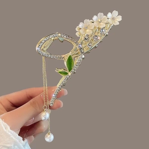 Detailed shot of golden floral hair claw clip with rhinestones and pearl tassels