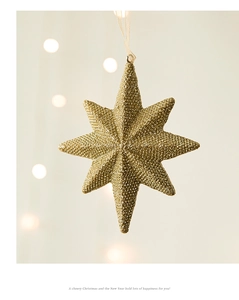 Détail d'une étoile de Noël octogonale dorée avec texture pailletée et ruban de suspension