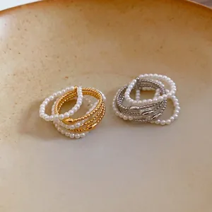 Minimalist gold and silver multilayer pearl open rings displayed on a ceramic dish