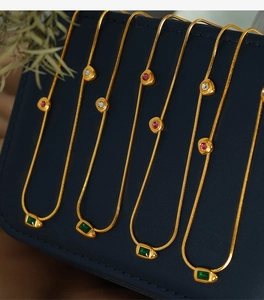 Detailed macro of gold snake chain necklaces with green zircon and colorful gemstones
