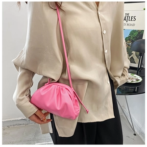 Detail of bright pink ruched cloud clutch bag featuring smooth leather texture and slim strap