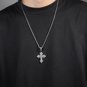 Vue macro du pendentif croix argenté avec zircons clairs sur chaîne torsadée