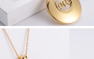 Detailed macro view of gold-plated circular pendant featuring hollowed LOVE engraving
