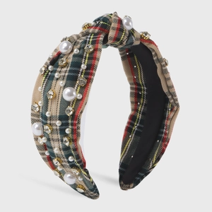 Detail of plaid headband with white pearls and sparkling rhinestones on checkered fabric