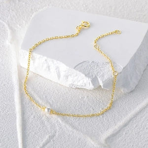 Detail of 925 sterling silver gold plated bracelet with a single round white pearl pendant