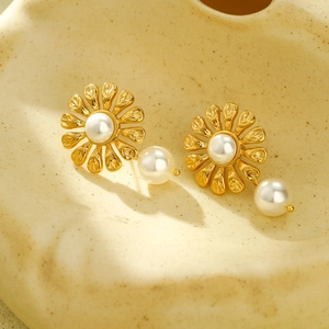 Golden flower titanium steel earrings with pearl drop charms for women in macro view