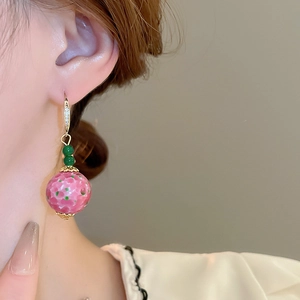 Detail of vintage French style earrings with pink floral beads and green accents on model
