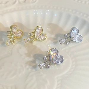 Detail of heart-shaped earrings with gold and silver finishes on a ceramic plate