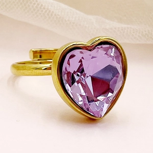 Gros plan d'une bague dorée ornée d'une grande pierre de zircone violette en forme de cœur