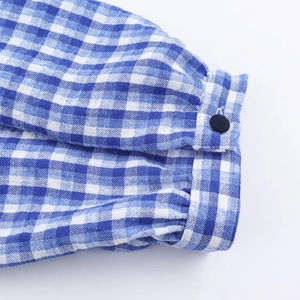 Detailaufnahme der blauen Karohemd-Manschette mit weißen Knöpfen und Leinentextur