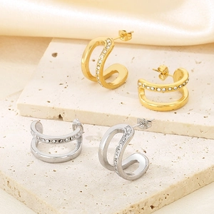 Close-up of gold and silver double-layer C-shaped earrings with micro-pave crystals