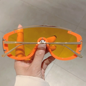 Detail of oversized orange sunglasses with yellow lenses and sleek gold metal temples