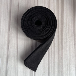 Detail of a black wool belt roll with reinforced stitching on a grey wooden surface