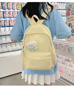 Pale yellow canvas backpack for students with a cute white puppy pendant and central pocket