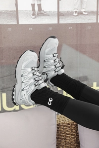 Detail shot of white mesh sports shoes with XA JXS 80 logo and black crew socks