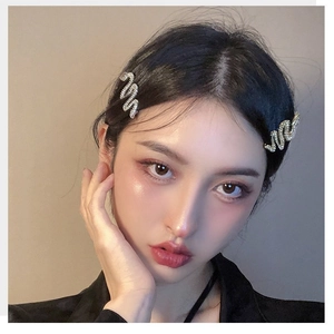 Sparkling silver snake-shaped hair clips with rhinestones worn by a model in a close-up view