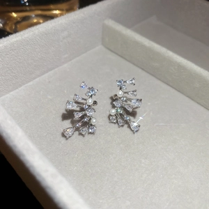 Macro detail of silver zircon bow earrings with pearls in a soft grey velvet jewelry box