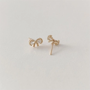 Close-up of golden bow stud earrings featuring sparkling teardrop zircon stones