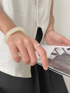 Close-up of minimalist double-layer frosted silver ring and translucent jade bangle
