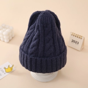 Close-up of navy blue cable knit beanie with thick textured patterns and folded cuff