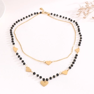 Double-layered necklace with gold heart charms and black faceted crystal beads on white