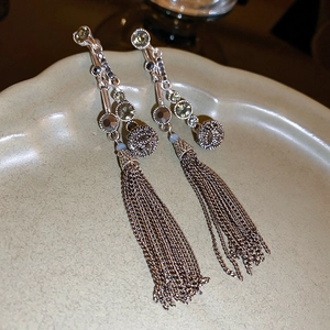 Macro shot of long silver tassel earrings with crystal rhinestones on a ceramic dish