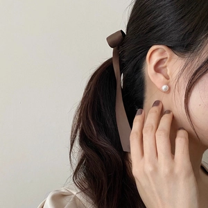 Elegant 925 silver earrings with baroque pearls and a brown satin ribbon bow on a model