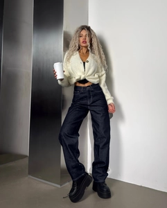 Détail d'un jean taille haute droit avec un cardigan en maille blanche et un café