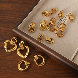 Detailed close-up of 18K gold-plated heart and twisted ring earrings on a jewelry tray