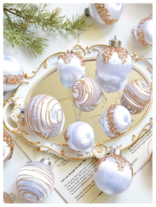 Detail von weißen Seiden-Weihnachtskugeln mit champagnerfarbenen Pailletten auf Tablett