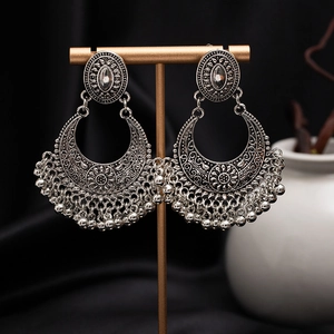 Close-up of vintage silver boho earrings with intricate hollow patterns and metal beads
