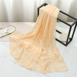 Detail showing elegant apricot chiffon scarf draped on a black minimalist metal hanger