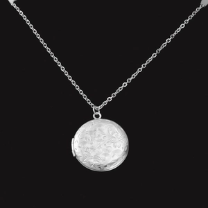 Détail de gravure sur médaillon rond en acier inoxydable 316L avec relief floral